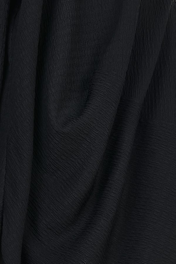 Vestido corto con tejido rugoso y en relieve. Trae manga larga y escote redondo. Detalle de caída asimétrica con aberturas laterales
