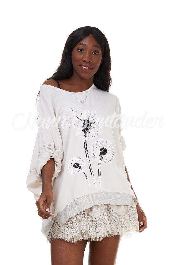 Blusa con motivo de diente de león. Trae manga larga remangable mediante cinta y botón y cuello redondo. Detalle de strass
