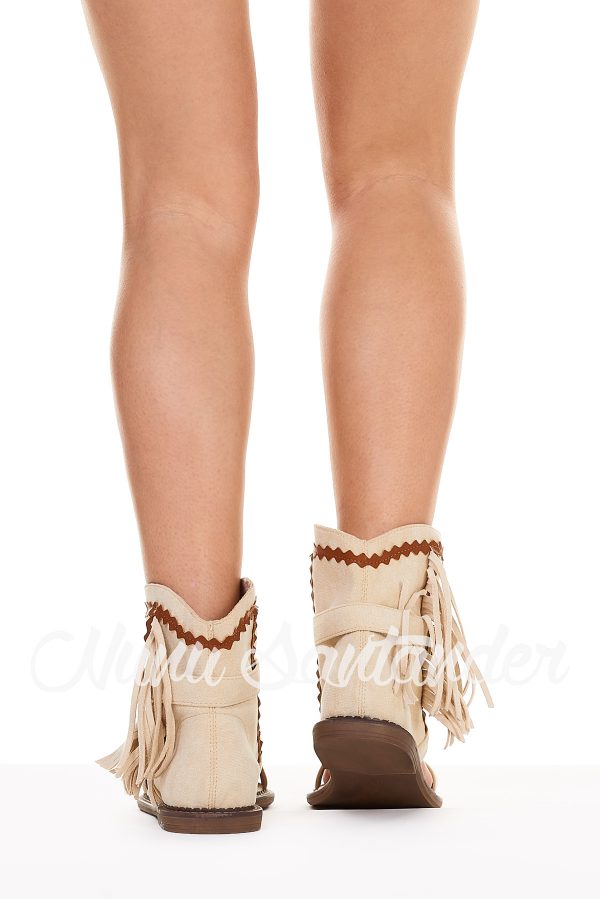 Sandalia estilo bota de antelina transpirable. Trae caña baja decorada con trenzados, con cierre mediante hebilla y flecos en el lateral.