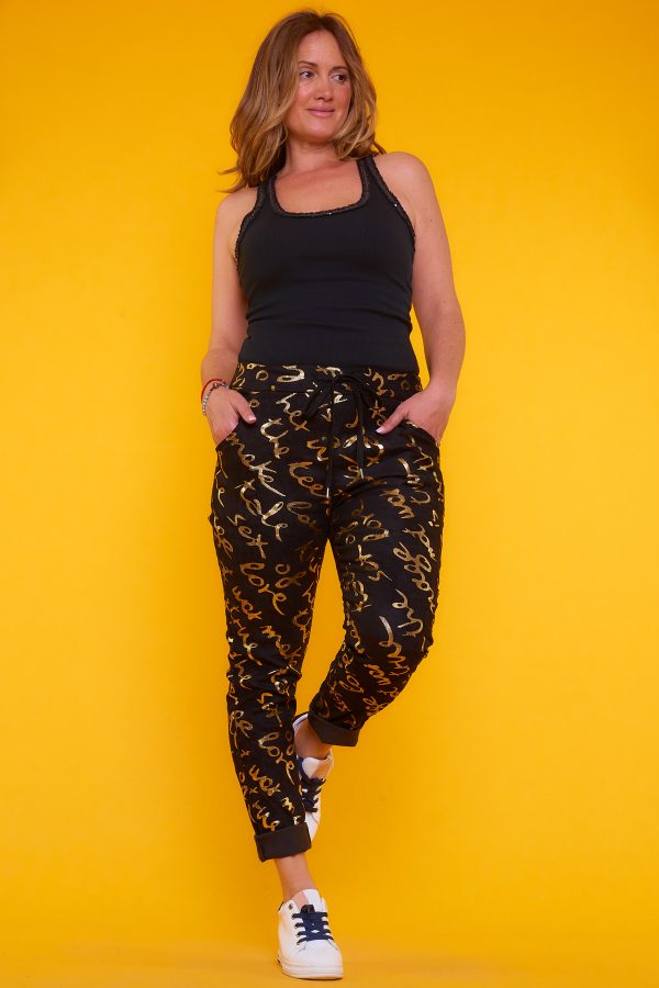 Pantalón Doty: pantalón elástico con detalles dorados brillantes, bolsillos funcionales y cintura ajustable. Diseño moderno, cómodo y sofisticado.