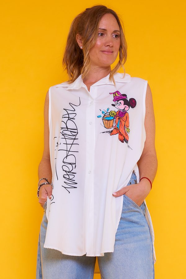 Una camisa sin mangas que tiene botones y cuello. La prenda tiene estampado y una apertura decorativa en sus laterales.