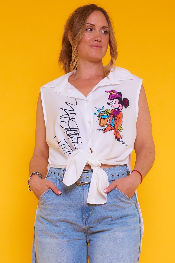 Una camisa sin mangas que tiene botones y cuello. La prenda tiene estampado y una apertura decorativa en sus laterales.