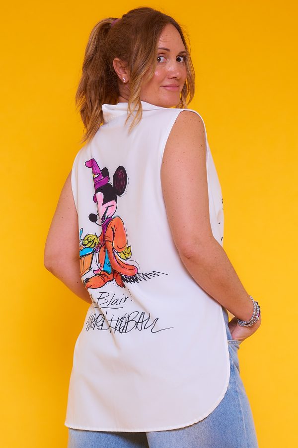 Una camisa sin mangas que tiene botones y cuello. La prenda tiene estampado y una apertura decorativa en sus laterales.