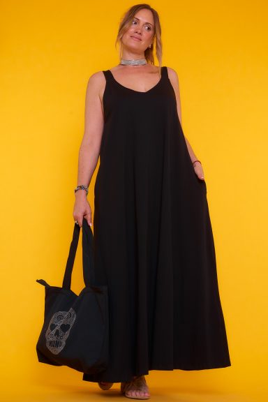 Un vestido elástico con tirantes que tiene bolsillos en sus laterales. Tiene una goma elástica en el borde de la parte trasera del escote.