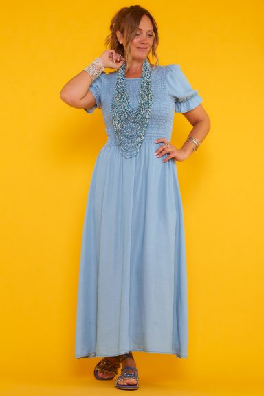 Un vestido largo de manga corta que tiene una pequeña apertura en la parte superior trasera y nido de abeja en toda la área del torso.