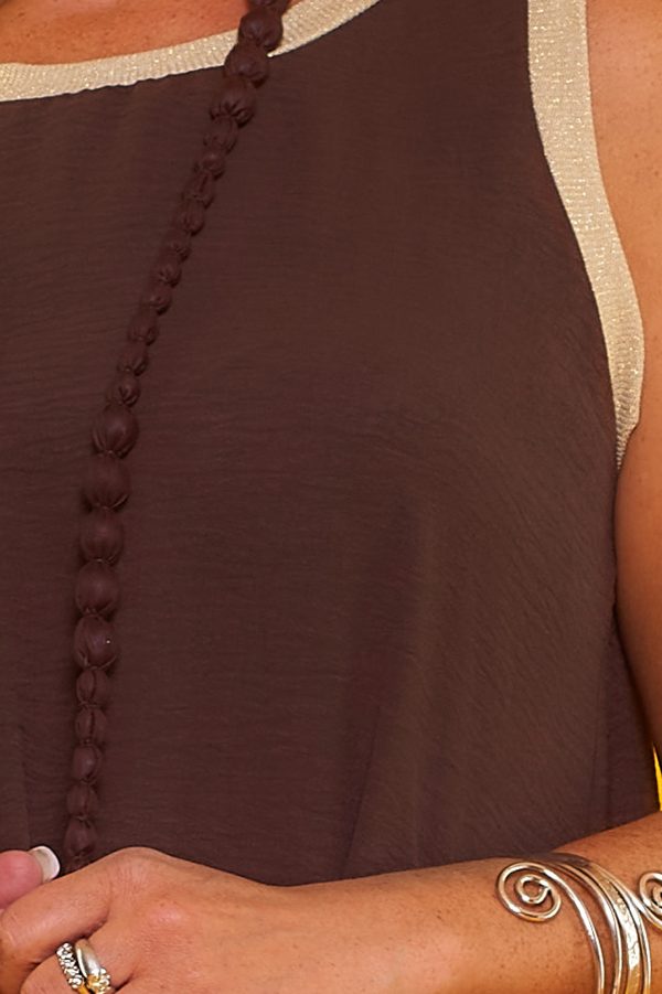 Un vestido largo elástico sin mangas que tiene una apertura en la parte inferior y tiene hilo metálico color dorado en sus bordes superiores.