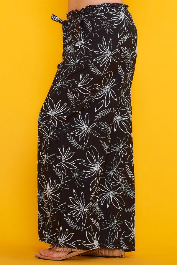Un pantalón estampado que tiene dos bolsillos laterales y una goma elástica en la cintura. Tiene un par de cintas para hacer nudo decorativo.