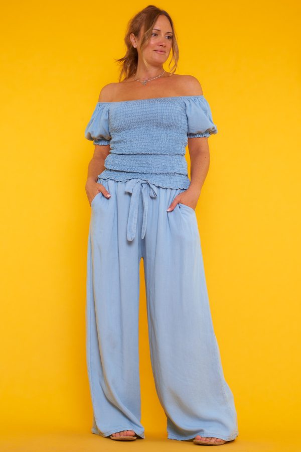 Una blusa que tiene escote palabra de honor y nido de abeja. Tiene goma elástica en los bordes del escote y las mangas.
