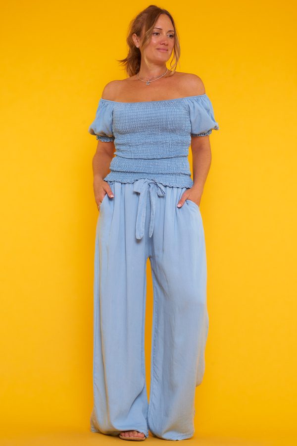 Una blusa que tiene escote palabra de honor y nido de abeja. Tiene goma elástica en los bordes del escote y las mangas.