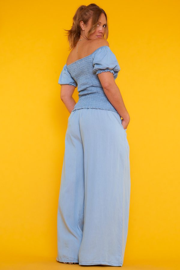 Una blusa que tiene escote palabra de honor y nido de abeja. Tiene goma elástica en los bordes del escote y las mangas.