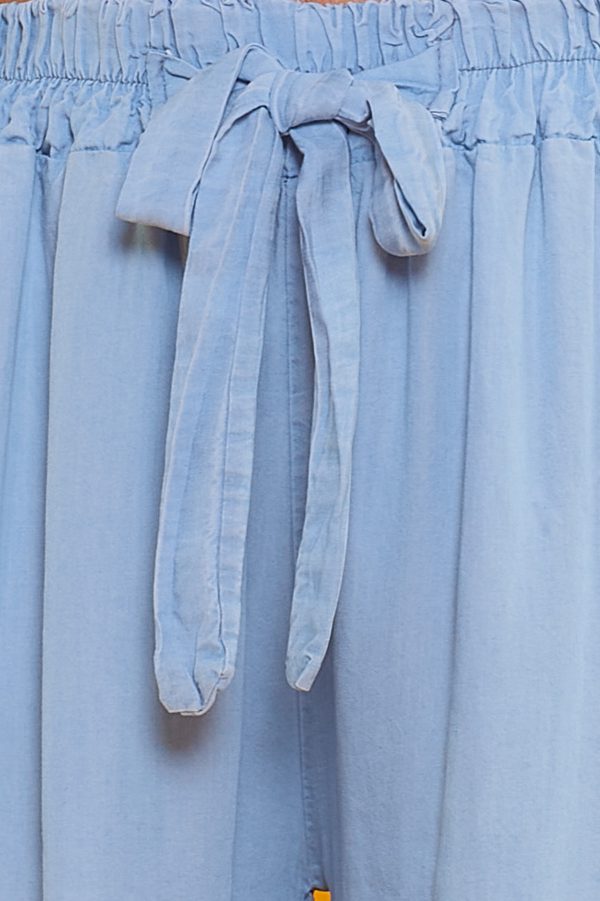 Un pantalón de pierna ancha que tiene dos bolsillos en sus laterales. Tiene goma elástica en la cintura y cintas para hacer nudo decorativo.