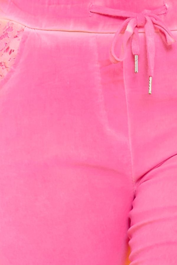 Un pantalón corto elástico que tiene bolsillos, una goma elástica en la cintura y cordones. Tiene color flúor y decoraciones en bolsillos.