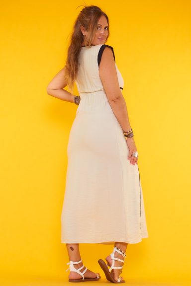 Un vestido largo sin mangas que tiene una especie de volante en esos bordes. Tiene escote en pico y un soporte en los hombros.