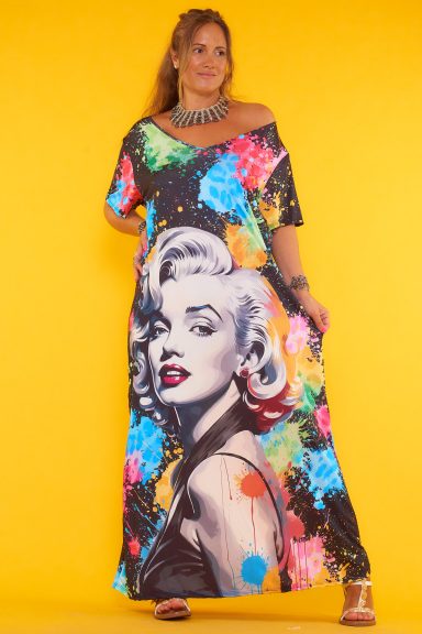 Un vestido largo que tiene un estampado que cubre toda la prenda y es de punto frío. Tiene manga corta y escote en pico.