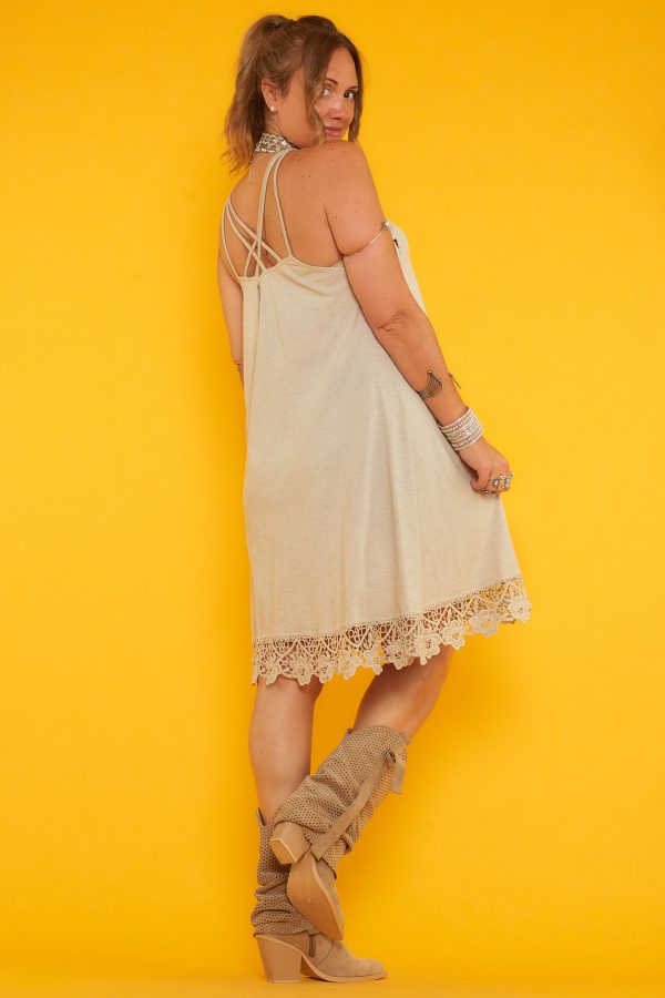 Un vestido corto elástico que tiene diseño de tirantes fijos cruzados en la espalda y detalle de crochet en su escote y parte inferior.