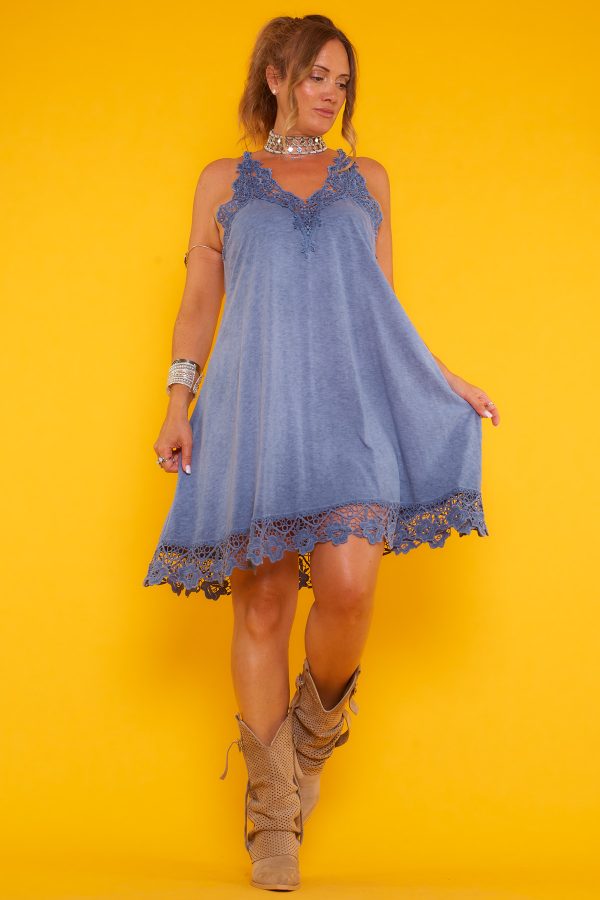 Un vestido corto elástico que tiene diseño de tirantes fijos cruzados en la espalda y detalle de crochet en su escote y parte inferior.