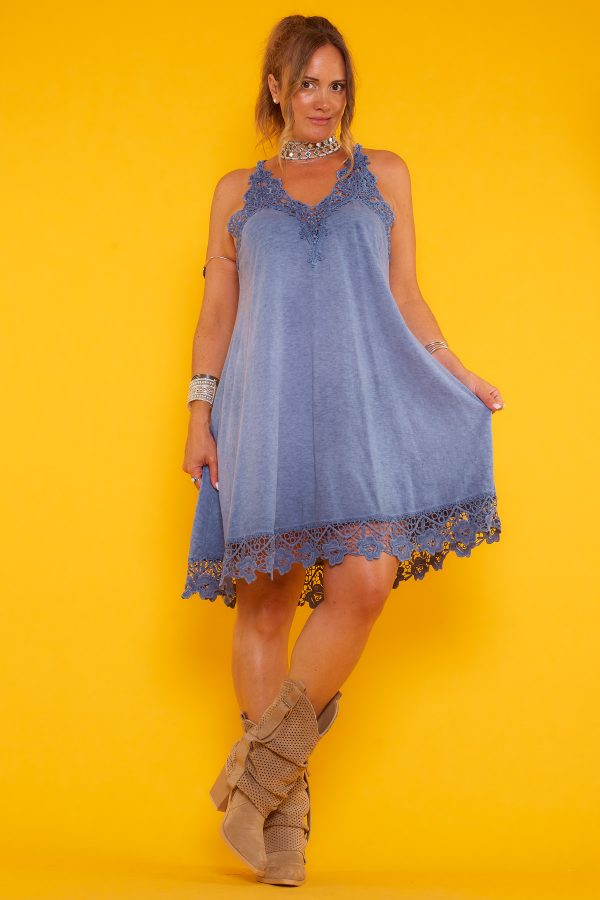 Un vestido corto elástico que tiene diseño de tirantes fijos cruzados en la espalda y detalle de crochet en su escote y parte inferior.