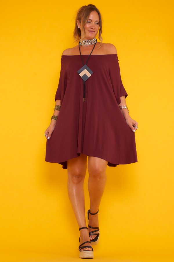 Un vestido corto elástico que viene con un colgante incluido. Tiene un corte asimétrico, un escote amplio y una especie de manga francesa.