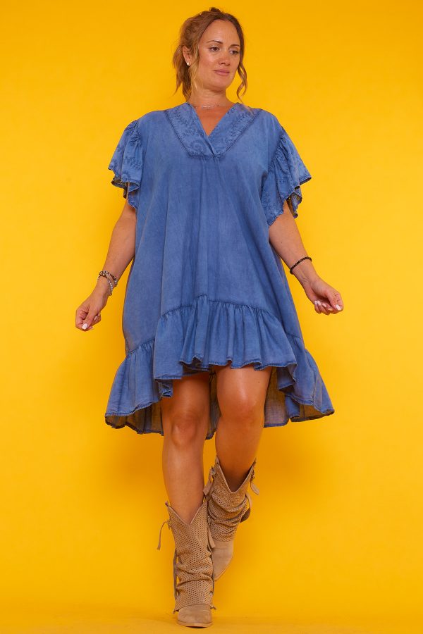 Un vestido corto que tiene volantes en la parte inferior y en las mangas. Tiene escote en pico y un corte asimétrico.