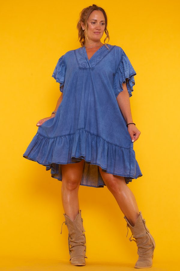 Un vestido corto que tiene volantes en la parte inferior y en las mangas. Tiene escote en pico y un corte asimétrico.