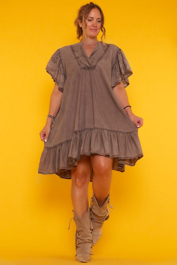 Un vestido corto que tiene volantes en la parte inferior y en las mangas. Tiene escote en pico y un corte asimétrico.