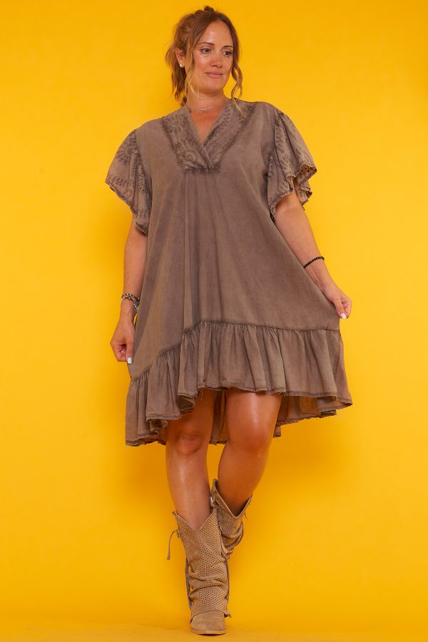 Un vestido corto que tiene volantes en la parte inferior y en las mangas. Tiene escote en pico y un corte asimétrico.