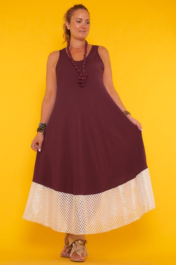 Un vestido largo sin mangas que se caracteriza por sus detalles en la parte inferior de orificios con sus bordes en color dorado brillante.