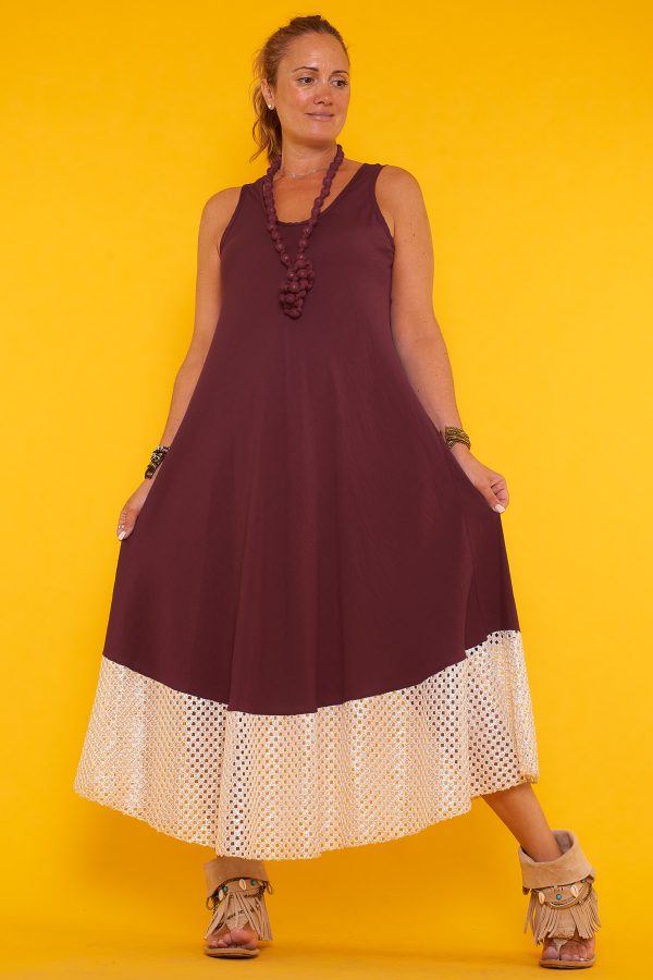 Un vestido largo sin mangas que se caracteriza por sus detalles en la parte inferior de orificios con sus bordes en color dorado brillante.