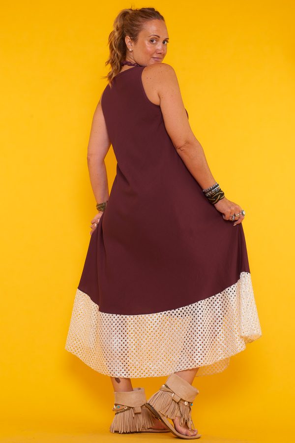 Un vestido largo sin mangas que se caracteriza por sus detalles en la parte inferior de orificios con sus bordes en color dorado brillante.