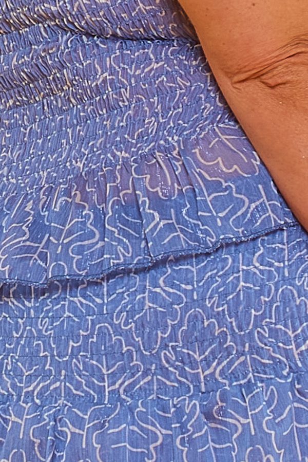 Un conjunto compuesto por una blusa y una falda pantalón. Ambas piezas tienen nido de abeja, volantes y un brillo disimulado color plateado.