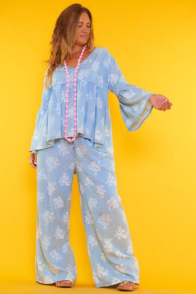 Un conjunto compuesto por una blusa y un pantalón completamente estampados. El pantalón tiene bolsillos y la blusa tiene mangas acampanadas.