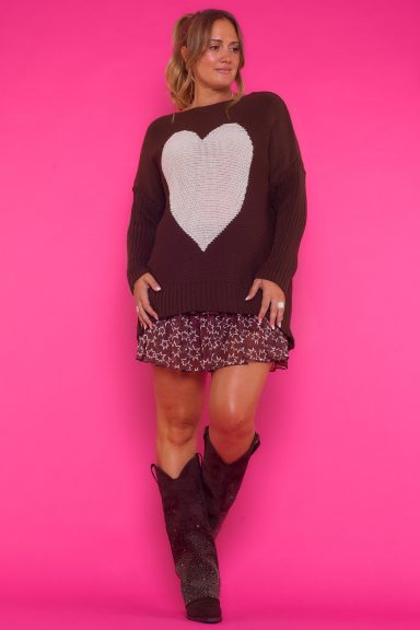 Un jersey de punto que es elástico de manga larga que tiene un diseño de un corazón en la parte frontal y un corte asimétrico.