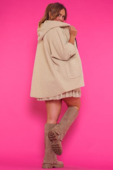 Una chaqueta elástica con corte asimétrico que tiene capucha, dos bolsillos frontales y una cremallera como mecanismo de cierre.