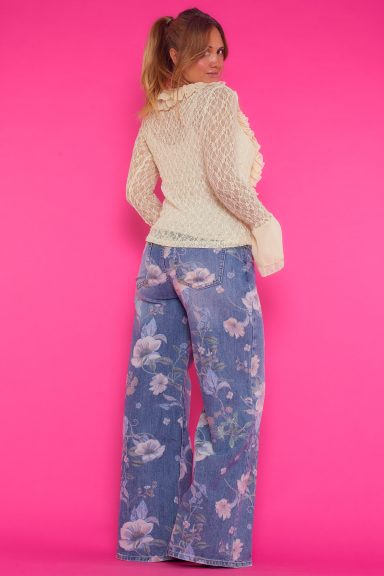 Una blusa elástica de encaje que se caracteriza por tener volantes en los bordes de su escote y por tener manga acampanada.