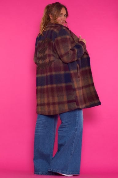 Un abrigo que tiene bolsillos frontales y cierre por medio de botones que se caracteriza por tener un estampado en su parte trasera.