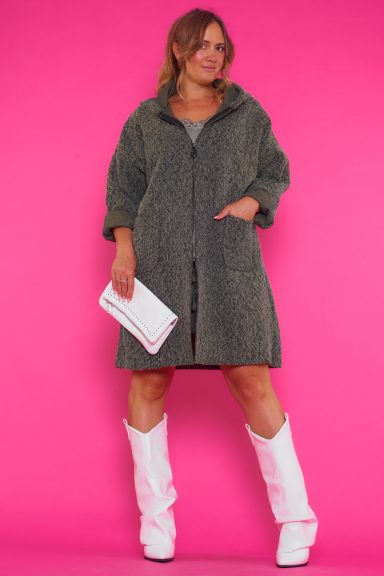 Una abrigo elástico largo con corte asimétrico que tiene capucha, dos bolsillos frontales y una cremallera como mecanismo de cierre.