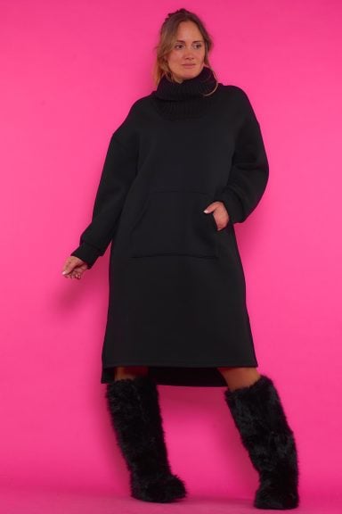 Un vestido largo elástico que tiene un bolsillo frontal y forro polar en su interior. La prenda tiene un cuello de tortuga de punto.
