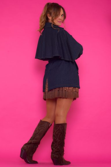 Una chaqueta vaquera elástica que tiene bolsillos y se cierra por medio de botones. Tiene un gran volante en la parte trasera y un cinturón.