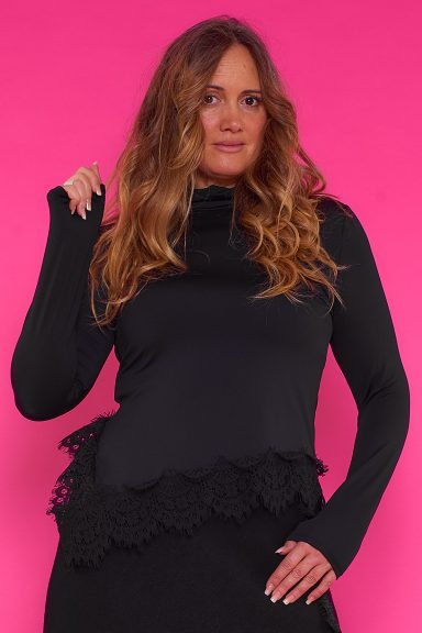 Blusa Asimétrica Con Encaje Linden Una blusa elástica de cuello alto que se caracteriza por tener un corte asimétrico con decoración de encaje en su parte inferior.