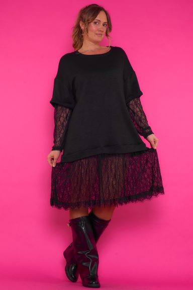 Un vestido largo con cuello redondo y manga larga que se caracteriza por tener decoración de encaje en su parte inferior y en sus mangas.