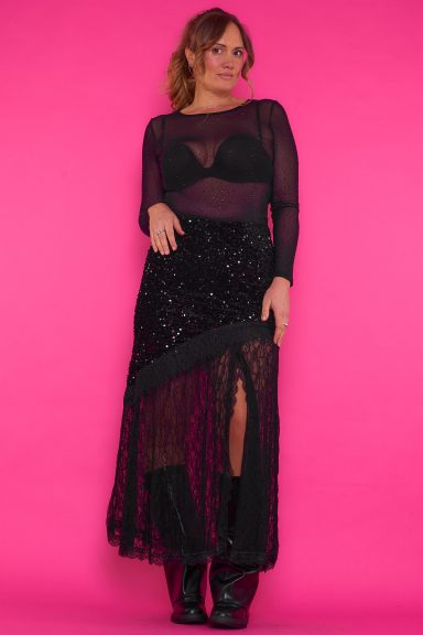 Una falda larga elástica que tiene una apertura en su parte frontal y también tiene lentejuelas aterciopeladas y decoración de encaje.