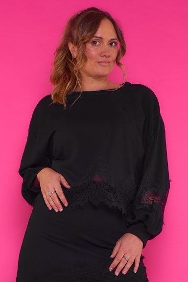 Una sudadera elástica de cuello redondo que se caracteriza por tener decoración de encaje en su parte inferior y en sus mangas.