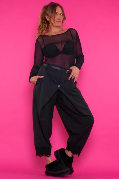 Un pantalón que viene con un cinturón incluido y decoración de encaje en la parte inferior. Tiene un diseño asimétrico con un botón frontal.