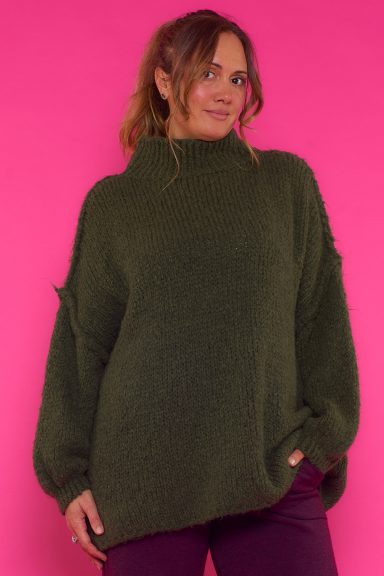 Un jersey elástico de punto que se caracteriza por tener un corte asimétrico y un cuello alto que estiliza la prenda.