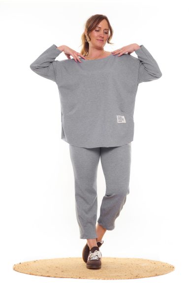 Un conjunto elástico compuesto por una sudadera y un pantalón. Ambas piezas tienen una etiqueta y un diseño minimalista.