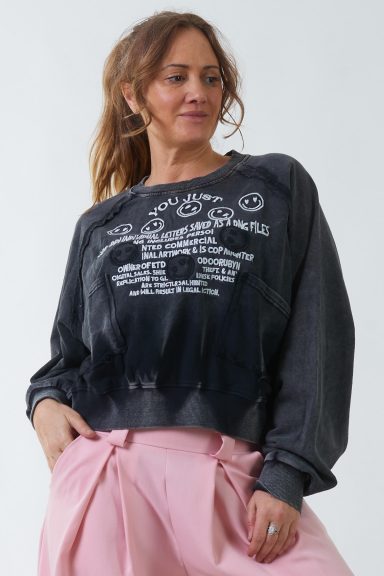 Una sudadera elástica estilo baggy que tiene manga murciélago y en la parte frontal un estampado con textura con dos bolsillos.