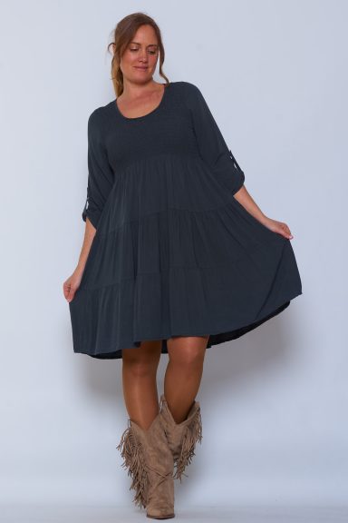 Un vestido elástico que tiene nido de abeja en su parte superior y botones en sus mangas para poder arremangarlas.