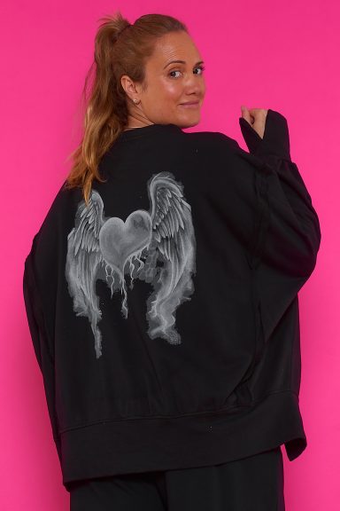 Una sudadera elástica de corte asimétrico que tiene dos pequeñas aperturas laterales y un estampado grande en la parte trasera de la prenda.