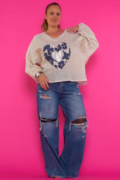 Un jersey que tiene escote en pico, un estampado en la parte frontal y un brillo disimulado en todo su tejido de diseño calado. 